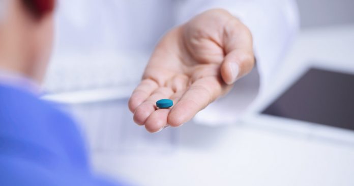 doctor man giving a blue pill to a senior man
